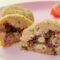 Bolinhos para bebês de batata recheados com carne moída, cortados ao meio, em um prato rosa com tomate e pepino