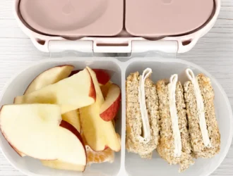 Lancheira saudável para escola em pote bento com fatias de maçã, gomos de mexerica e sanduíche integral de cream cheese