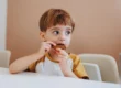 Criança comendo cookie de chocolate sem açúcar, um dos doces do cardápio de Dia das Crianças saudável