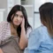 Como lidar com filhos adolescentes: Filha adolescente com expressão de desânimo ouvindo a mãe durante uma conversa no sofá de casa